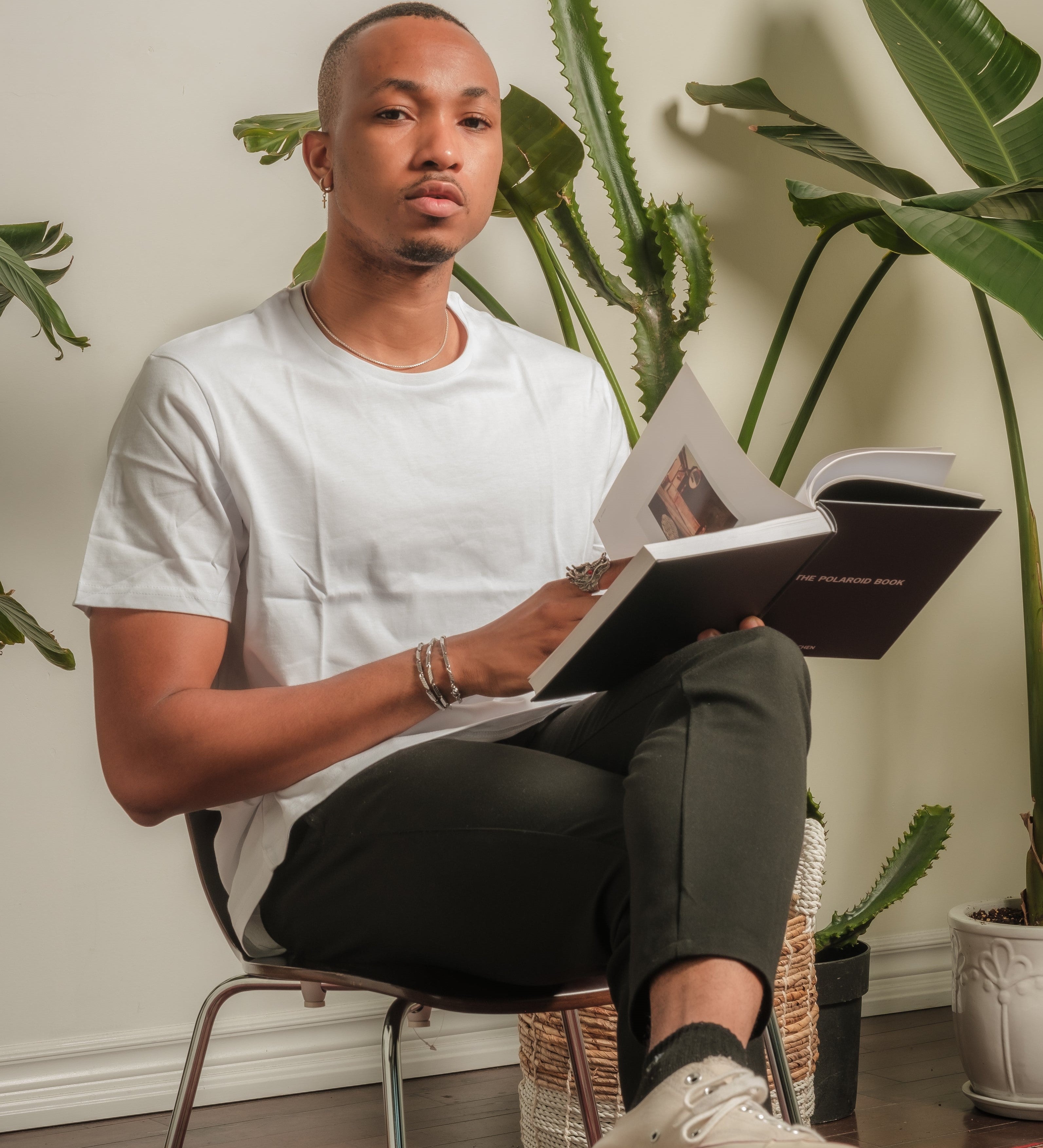 person sits in front of a wall lined with potted plant